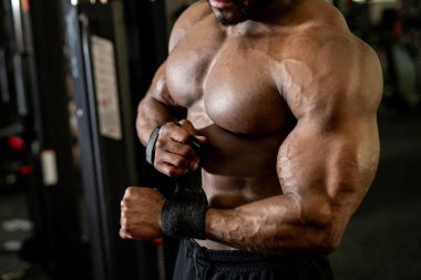 Spor salonunda egzersiz yapan adam. Çıplak gövdeli genç bir adamın modern beden eğitimi geçmişine özel bandajlar koyduğu fotoğraf. Kuvvet ve motivasyon kavramı