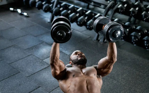 Hombre Afroamericano Fuerte Haciendo Ejercicio Con Dos Pesas Mientras Está —  Fotos de Stock