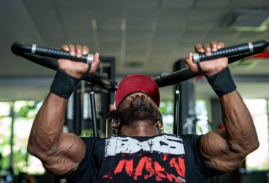 Yakışıklı kaslı adam spor salonunda sıkı çalışıyor. Güçlü vücut geliştirici ağır egzersiz yapıyor..