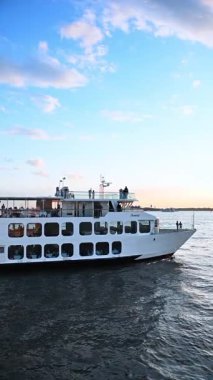 New York, USA, 1 August 2025: White cruise boat with numerous people travel by the river. Fun time spending at river tour. Vertical video.