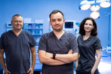 Doktor ekibi ameliyathaneye. Bir grup tıp doktoru ameliyathanede birlikte duruyorlar, kendilerine güveniyorlar..