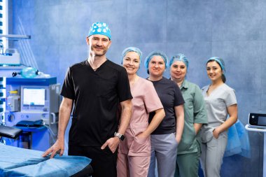 Ameliyathanede poz veren cerrahlardan oluşan tıbbi ekip. Cerrahlar ve hemşireler modern ameliyathanede cerrahi ekipmanlarla birlikte poz veriyorlar..