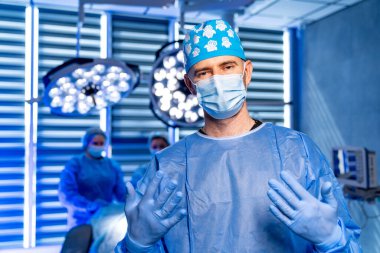 Cerrah neşteri ameliyathanede tutuyor. Ameliyat sırasında parlak cerrahi ışıklarda neşter tutan eldivenli cerrahları kapatın..