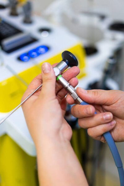 Доктор настраивает эндоскоп. Крупный план рук, регулирующих устройство эндоскопа в клинической среде.