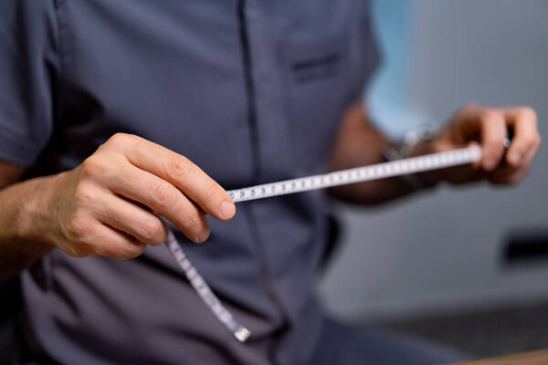 Доктор измеряет с помощью медицинской ленты. Пластический хирург проводит измерения ленты во время консультации, чтобы подготовиться к процедуре.
