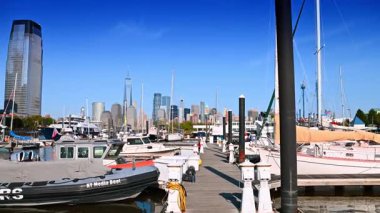 New Jersey, ABD, 19 Ağustos 2025, yakınındaki yat ve teknelerle ahşap rıhtımın yanından geçiyor. Jersey City, ABD 'deki yat kulübü. Arkaplanda Manhattan silueti.