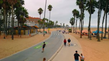 Los Angeles, ABD, 29 Ağustos 2025: İnsanlar Santa-Monica plajı boyunca yürüyor, koşuyor ve kayıyorlar. Pasifik Okyanusu kıyısında kasvetli bir gün..