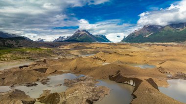 Alaska 'daki buzulların ve buz tepelerinin havadan yakından görüntüsü. Alaska vadisindeki buzul arazisi ve buz tepeleri mavi gökyüzü ve bulutların altında.