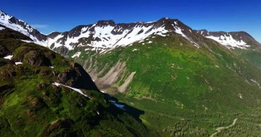 Tepesinde karla kaplı yemyeşil dağlar. Alaska, ABD 'nin muhteşem doğası. Hava görünümü.