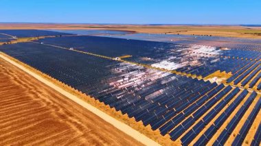 Geniş güneş panelleri yeşil enerji üretiyor. Güneşli bir günde kırsal bölgedeki insansız hava aracı görüntüleri..