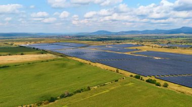 Bölgeyi kaplayan geniş bir fotovoltaik hücre alanına yaklaşıyoruz. Güneş panelleri güneşten güç topluyor. İnsansız hava aracı görüntüleri.