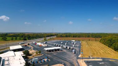 29 Haziran 2025, Chicago, ABD: Benzin istasyonuna ve park etmiş kamyonların olduğu bir otoparka yaklaşıyoruz. Arka planda bir otoyol ve yemyeşil ormanlar. Hava görünümü.