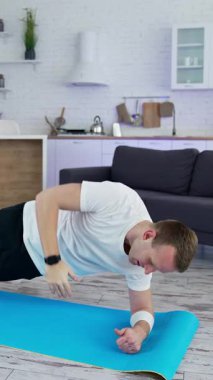 Sağlıklı ve güçlü bir adam içeride antrenman yapıyor. Karantina evde çalışıyor. Dikey video