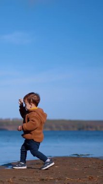 Küçük çocuk nehre yaklaşıyor. Kafkas çocuk suya iki taş attı. Dikey video