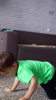 Yerde sürünen sevimli neşeli çocuk. Mutlu çocuk evdeki odasında oynuyordu. Dikey video