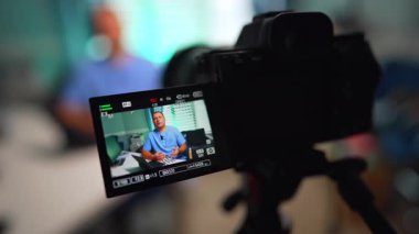 Kamerada mavi üniformalı beyaz bir erkek var. Kapatın. Tıbbi vlog içeriği oluşturma. Seçici odak.