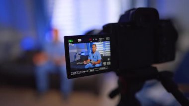 Mavi üniformalı bir adam modern bir kameranın önünde konuşuyor. Kapatın. İnternet günlüğü konsepti. Seçici odak.