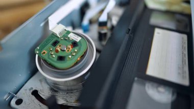 Makara, bant ona değdiği anda dönmeye başlar. VHS oynatıcının çalışmalarını inceliyorum. Kapat..