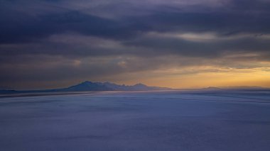 Bonneville Tuz Düzlükleri üzerindeki uzak dağ manzarası. Gün batımında Bonneville Tuz Düzlükleri 'nin geniş tuz düzlüklerinde ufuktaki dağların insansız hava aracı fotoğrafı..