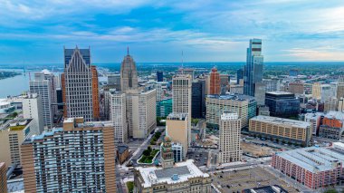 Detroit ufuk çizgisi yukarıdan görünüyor. Detroit şehir merkezinin insansız hava aracı görüntüsü. Yüksek binalar ve açık mavi gökyüzü altındaki şehir şebekesi..