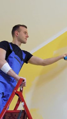 Daire dekorasyonu ve ev inşaatı. Kafkasyalı adam duvarı silindirle boyuyor.