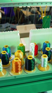 Renkli dikiş ipliği olan endüstriyel makineler. Endüstriyel dikiş makinesinde farklı renk ipliklerinin makaralarını ayarlar