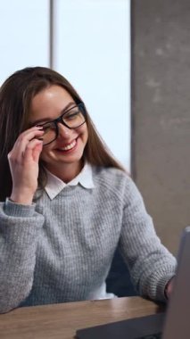 Gözlük takan güzel esmer dizüstü bilgisayarında çalışıyor. Kadın şaşkınlıkla bilgisayar ekranına bakıyor ve gözlüklerini çıkarıyor. Dikey video