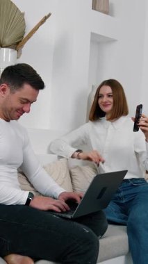 Modern pozitif insanlar iletişim için aletler kullanırlar. Adam dizüstü bilgisayarda yazıyor ve kadın selfie çekiyor. Dikey video