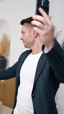 Atletik beyaz adam video konuşması yapıyor. Adam arkasından bir şeyi işaret ediyor ve yana dönüyor. Dikey video