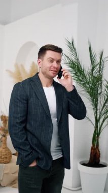 Ceket giyen bir adam telefonda konuşuyor. Akıllı telefonda arkadaşça bir konuşma ve bolca kahkaha. Dikey video