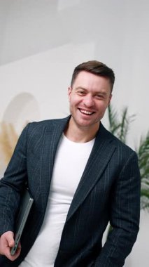 Elinde dizüstü bilgisayar tutan mutlu, beyaz bir adam. İşadamı bilgisayarını açar ve daktilo eder. Dikey video