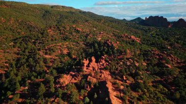 Parlak güneş yeşillikle kaplı kırmızı kil kayaları aydınlatıyor. ABD 'nin Utah eyaletindeki Capitol Reef Ulusal Parkı' nda insansız hava aracı uçuşu..