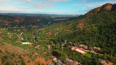Kayalık araziyi kaplayan ender yeşillik. Dağ eteğindeki vadideki evler. Utah, ABD.