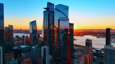 Manhattan 'daki cam gökdelen grubuna yaklaşıyoruz. Arkaplanda gökyüzünü boyayan güneş ışığı batıyor.