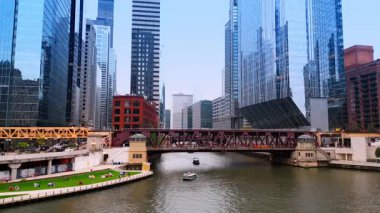Chicago, ABD, 29 Haziran 2025: İnsanlar Chicago Nehri 'nin kıyısındaki yeşil çimlerde dinleniyor. Çarpıcı şehrin yüksek binalarına alçak açılı bir bakış açısı..