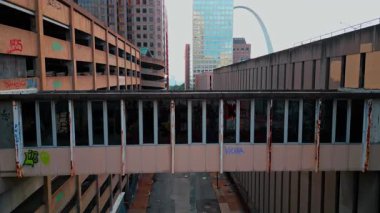 Saint Louis USA, 14 Ağustos 2025: Grafiti, kırık camlar ve paslı elementlerle terk edilmiş eski bir bina. Arka planda modern gökdelenler. St. Louis, Missouri, ABD. Hava görünümü.