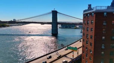 Arabalar Doğu Nehri 'nin sularında yol kenarına ilerliyor. Brooklyn Köprüsü ve Manhattan ufuk çizgisinde.