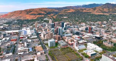 Modern Salt Lake City 'nin insansız hava aracından şehir manzarası. Yamaçtaki kentsel alanla dağlara yaklaşıyoruz..