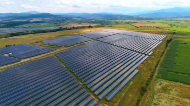 Fotovoltaik enerji santralinin hava manzarası. Geniş bir fotovoltaik enerji santralinin panoramik dron görüntüsü temiz, sürdürülebilir enerji üretiyor.