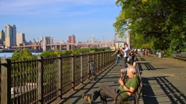 New York, ABD, 9 Ağustos 2025: Manhattan ufuk çizgisi manzaralı Brooklyn Heights gezinti güvertesi. İnsanlar rahatlar ve Brooklyn Heights gezinti güvertesinden Manhattan silueti ve Brooklyn Köprüsü manzarasının keyfini çıkarırlar..