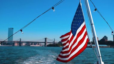 Doğu Nehri 'nden geçen teknede Amerikan bayrağı asılı. Manhattan Köprüsü ve Brooklyn Köprüsü.