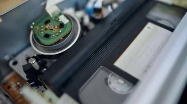 Video oynatıcının içine gir ve kapat. VHS mekanizması hızla döner ve sonra kaset fırlar.