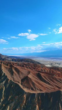 Bitki örtüsü olmayan harika tepeli dağlar. Bulutların arasından geçen güneş ışınları ABD 'deki Ölüm Vadisi Ulusal Parkı' nı aydınlatıyor. Dikey video.