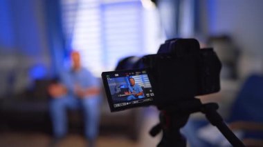 Mavi üniformalı adam modern kameranın önünde konuşuyor. Doktor ofisinde bir video kaydediyor. Seçici odak.