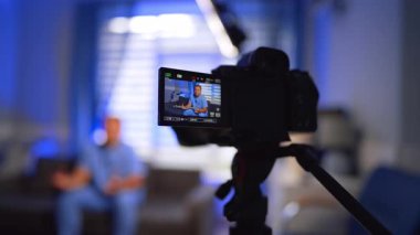 Tripod 'daki kamera mavi üniformalı bir doktorun kaydını tutuyor. Sıhhiye video bloğu için bir video hazırlıyor. Seçici odak.