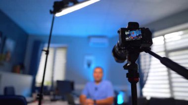 Çalışan kamera bir adamın video kaydını kaydediyor. Mavi üniformalı doktor tıbbi içerikten bahsediyor. Düşük açı. Seçici odak.