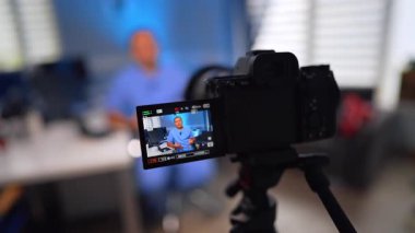 Mavi üniformalı beyaz bir doktor masasında oturmuş konuşuyor. Sıhhiye ofisinde bir video bloğu oluşturuyor. Seçici odak.