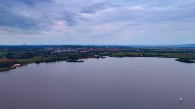 Göl manzarası ve küçük kasabanın yakınındaki yeşil alanlar. Huzurlu göl manzarası ve sakin bir Avrupa kasabasını çevreleyen yeşil manzara.