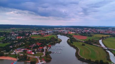 Marina ve tarlaları olan küçük bir Avrupa kasabasının havadan görünüşü. Akşam vakti etrafı tarım arazileri ve marinalarla çevrili büyüleyici Avrupa kasabasının insansız hava aracı manzarası.