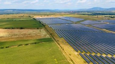 Geniş fotovoltaik (PV) hücreleri olan bir kırsal bölge. Yerleşim alanı ve arka plandaki sıradağlar. Hava görünümü.